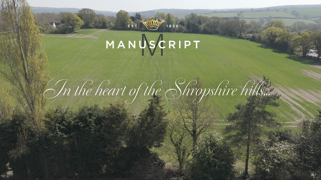 Load video: A drone overhead view of the rolling Shropshire hills, which then pans to the Manuscript Pen Co headquarters building. The text reads, in the heart of the Shropshire hills, our legacy continues. 